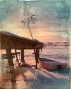Rowboat on snowy shore by pier at serene dawn with pastel sky, distant boats on water.
