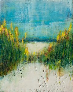Sandy path to a beach, bordered by tall grasses under a clear blue sky.